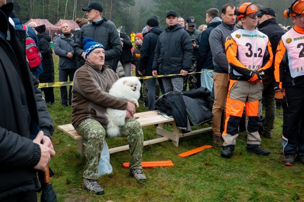 President Lukashenko sitting with a small white dog among a crowd of people 