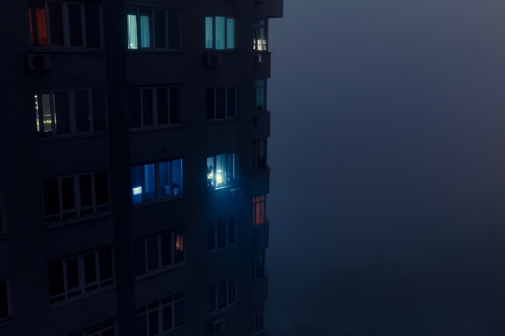 Person shining flashlight from a dark apartment building