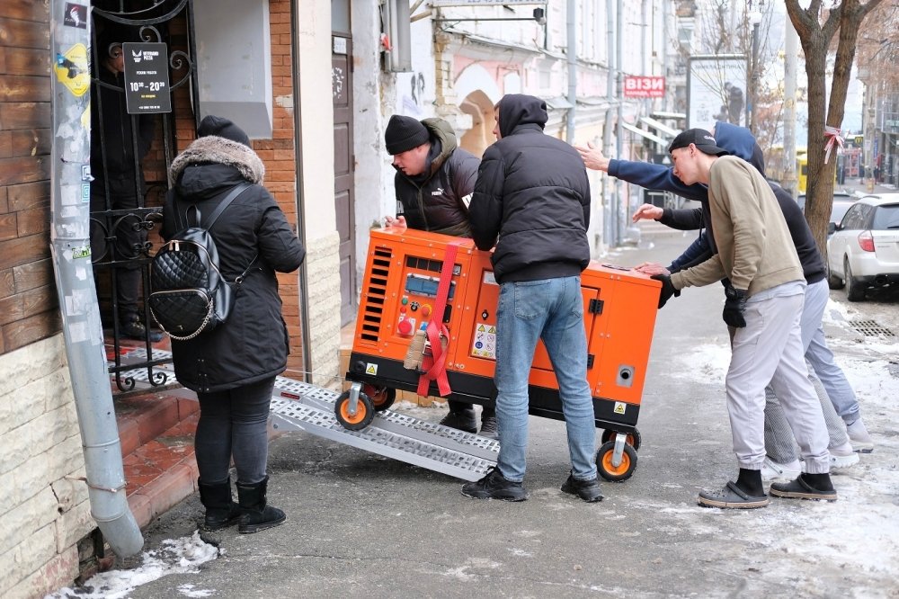 Group of men bringing an orange generator through a doorway