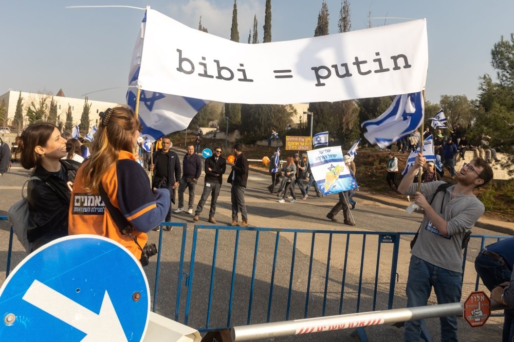 Protesters carrying sign comparing Netanyahu and Putin