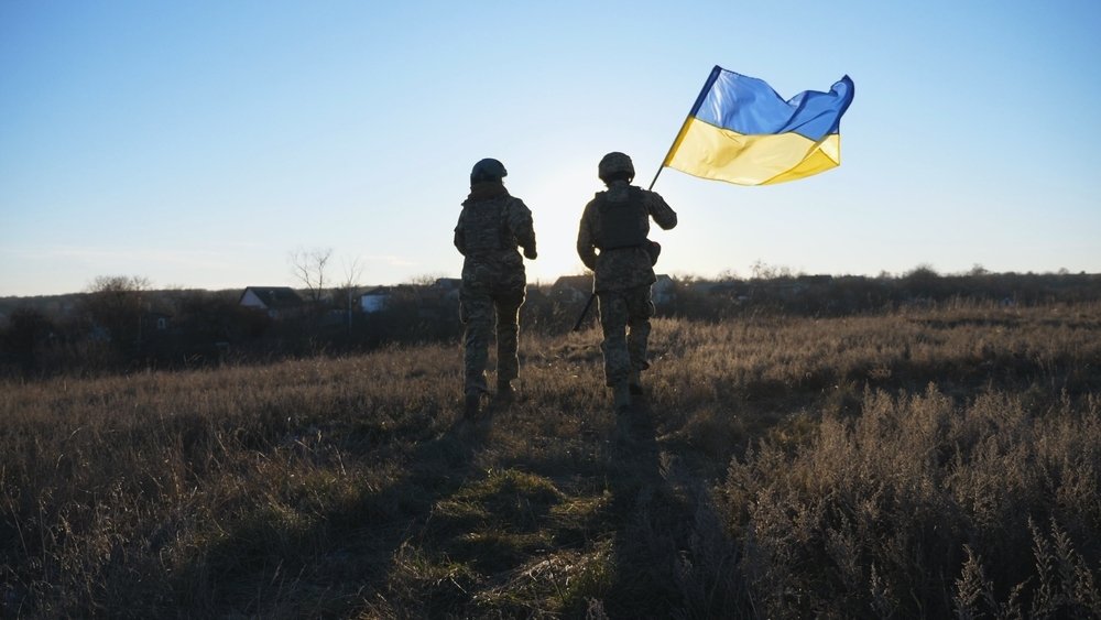 Soldiers waving a Ukrainian flag in a field