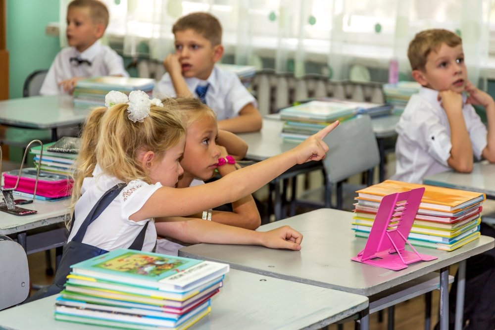 Odessa, Ukraine - September 1, 2015: elementary school students at their desks with textbooks on the first day of the school year. Feast Day of Knowledge. Beginning of a new academic year.