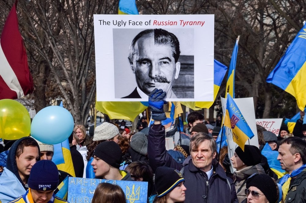 Protest with Ukrainian flags and poster comparing Putin to Stalin