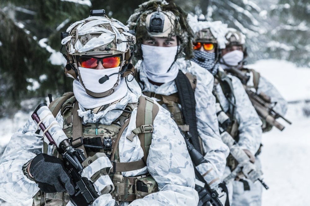 Action in cold conditions. Squad of soldiers with weapons in forest somewhere above the Arctic Circle