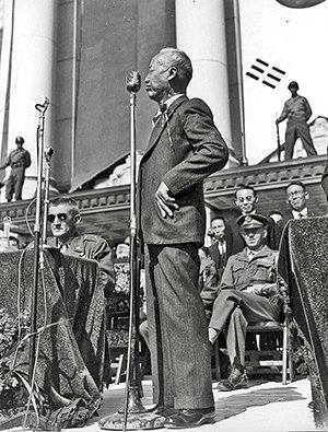 Syngman Rhee standing at a podium and giving a speech.