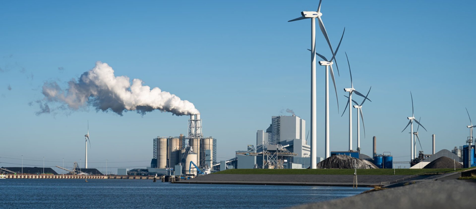 Fossil fuel (coal) power station and wind turbines in the Eemshaven generating power. Energy transition concept.