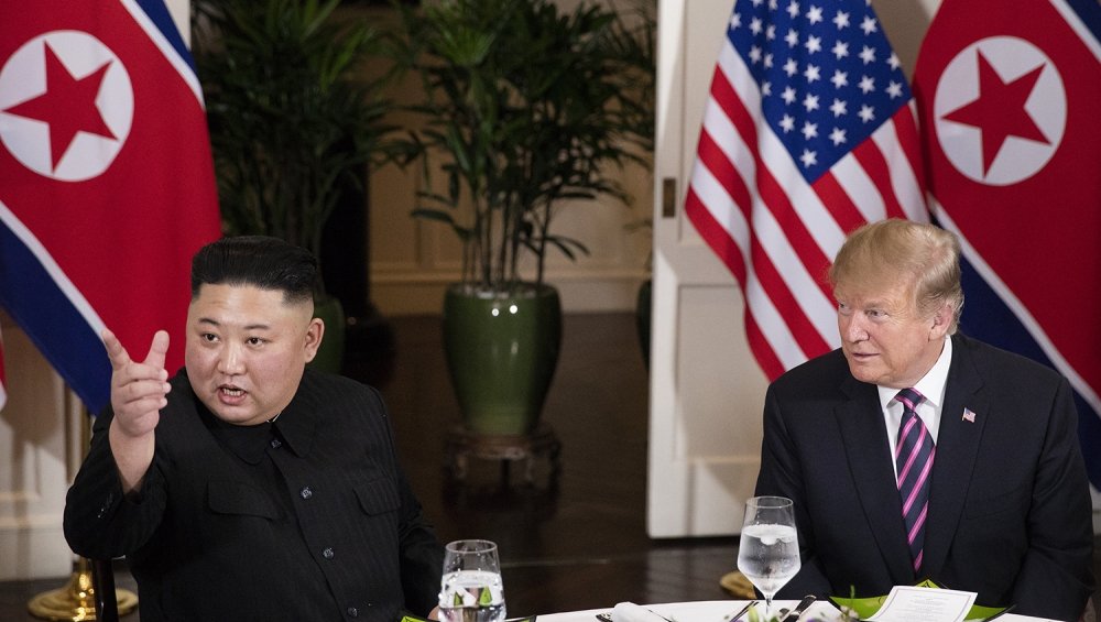 Kim Jong Un sits at a dinner table next to Donald J. Trump