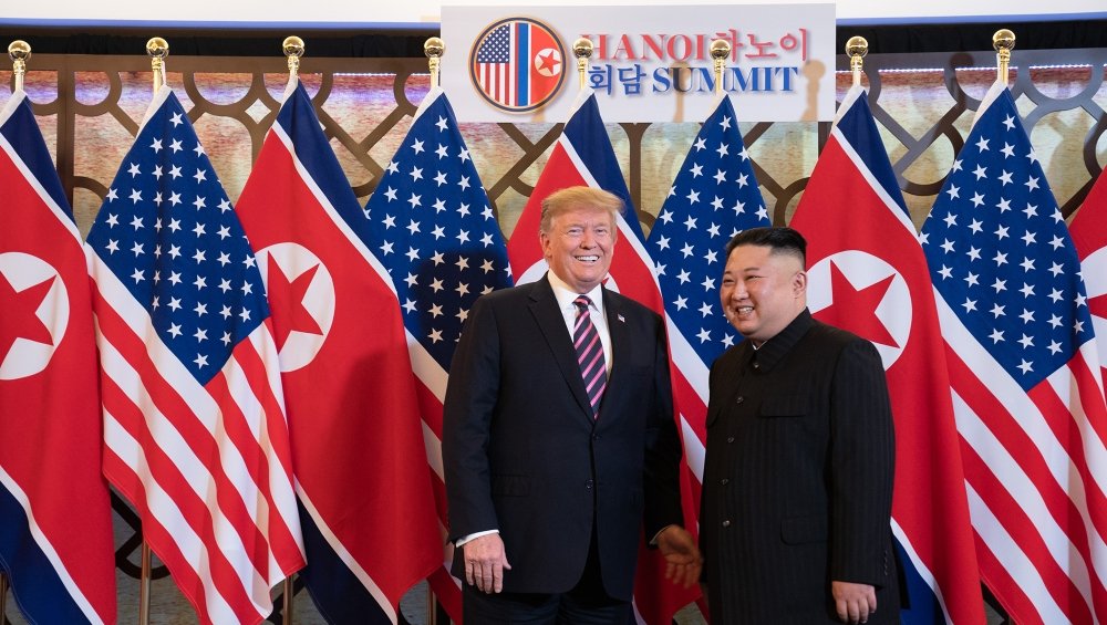 President Donald Trump stands with Chairman Kim Jong Un in front of the flags of the U.S. and North Korea