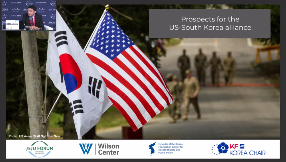 A screencap showing Dr. Kim Joonhyung speaking with an image of South Korean and U.S. flags in the background.