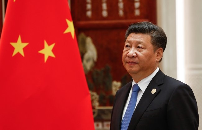 Xi Jinping standing next to the flag of China.