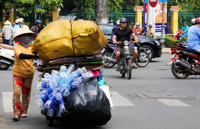 A person pushing a cart of plastic waste