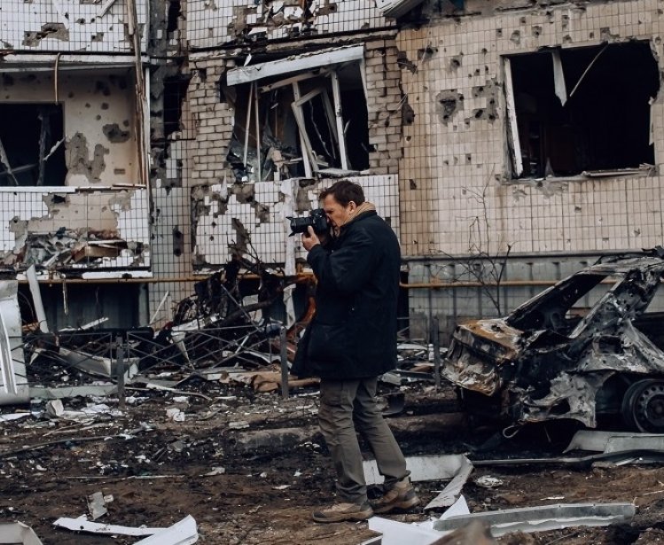 photographer in front of a bombed building in Kyiv, Ukraine