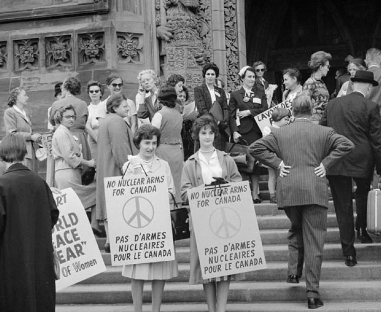 Women on steps holding signs "No Nuclear Arms for Canada