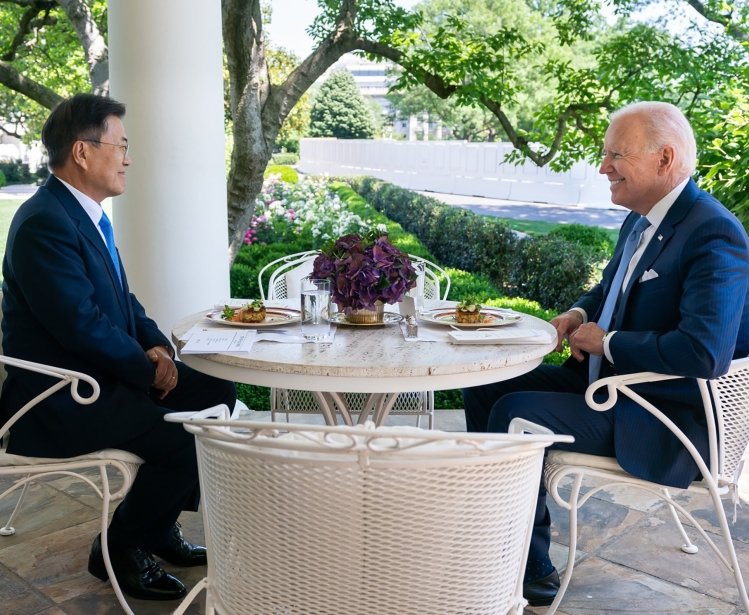 President Moon Jae-in sits opposite of President Joe Biden at an outdoor table.