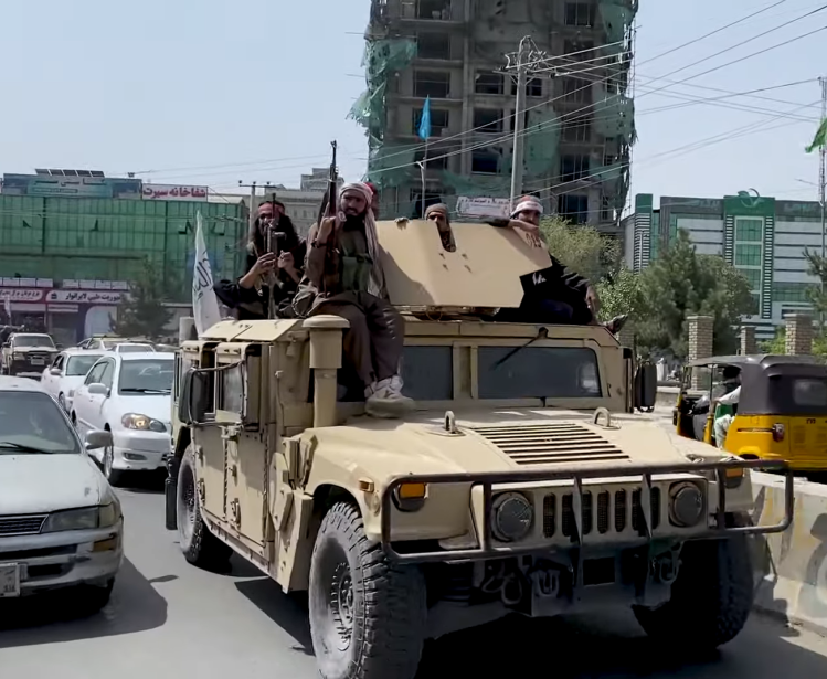Taliban fighters riding a tank in the streets of Kabul.