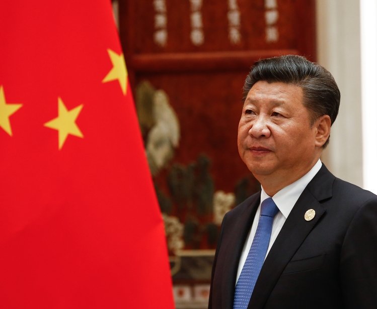 Xi Jinping standing next to the flag of China.