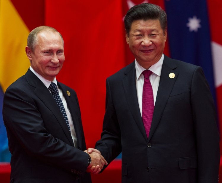 A picture of Xi Jinping and Vladimir Putin shaking hands.