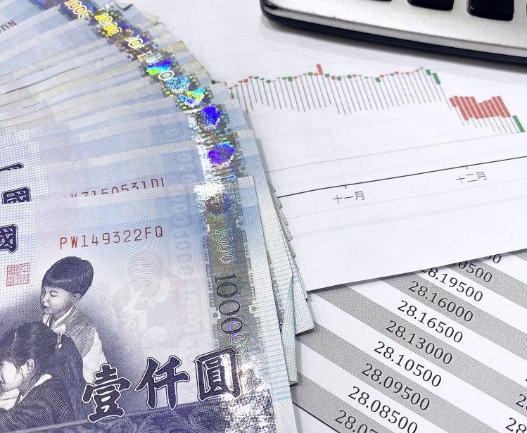 A stack of currency from Taiwan piled with spreadsheets and other reports.