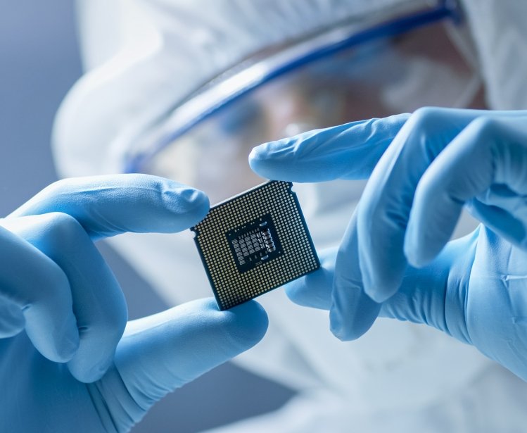 A person in a clean suit holding up a computer chip