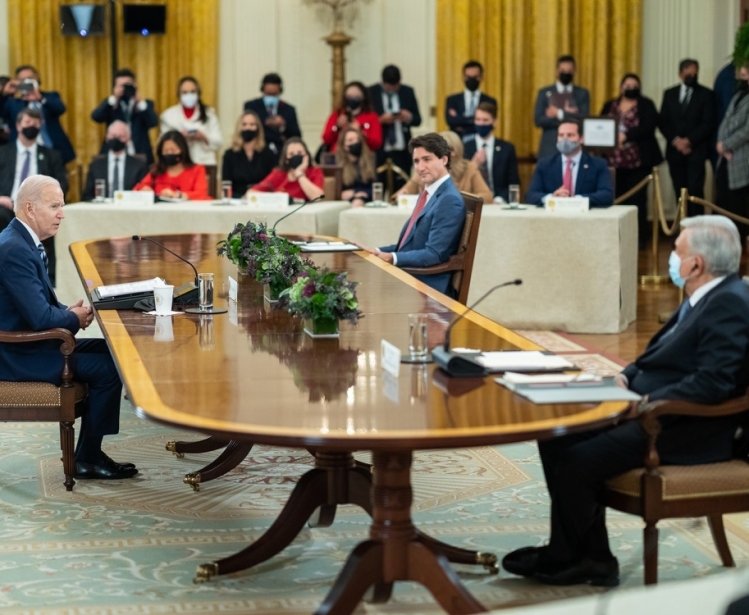 President Biden, President Lopez Obrador, and Prime Minister Trudeau sit at a table and talk
