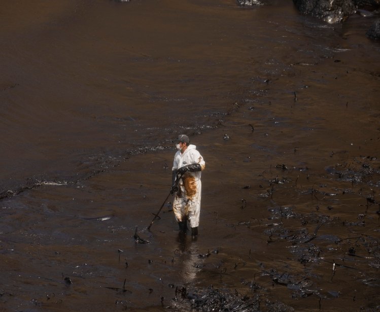 Callao, Peru; January 19, 2022: Workers clean after an oil spill, on Cavero Beach in the Ventanilla district of Callao. From La Pampilla Repsol refinery