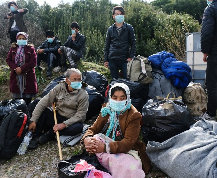 Refugees with masks awaiting transport in Greece