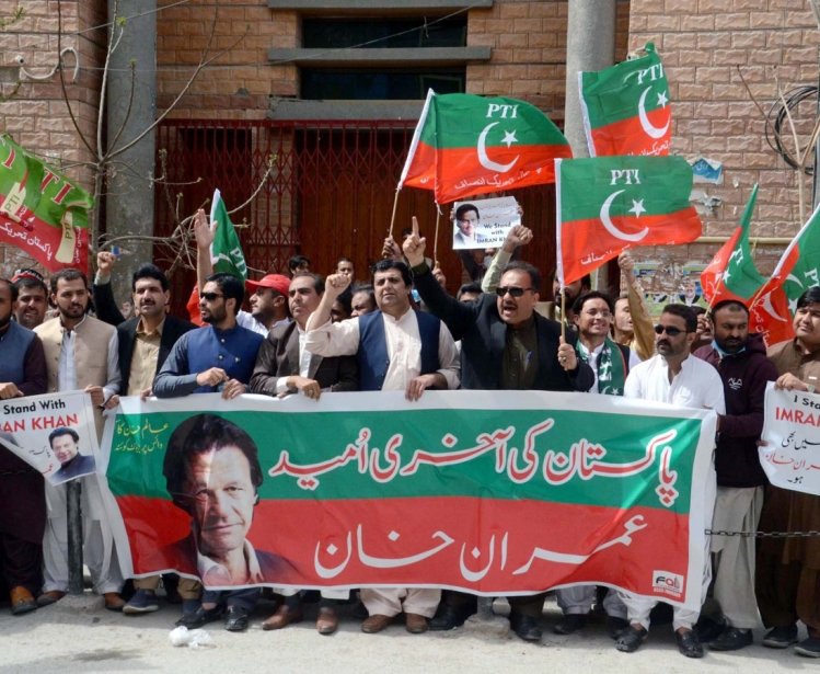 A group of Tehreek-e-Insaf supporters with a large banners and signs.