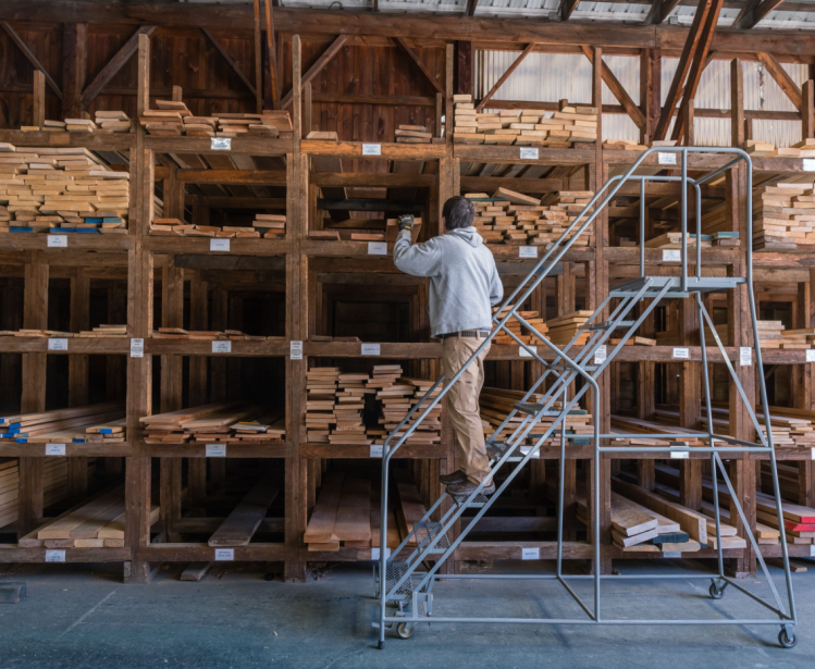 A man chooses wood from stacks of lumber