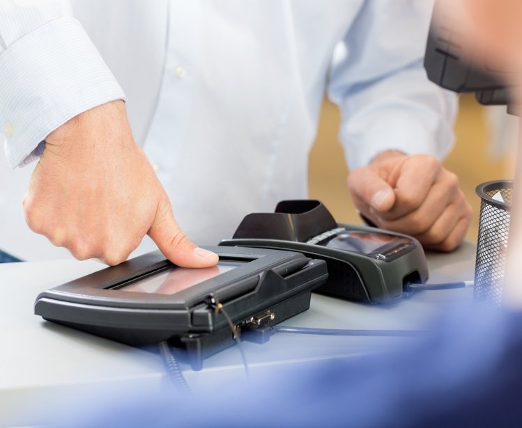 Midsection of customer giving thumb impression to make payment in pharmacy