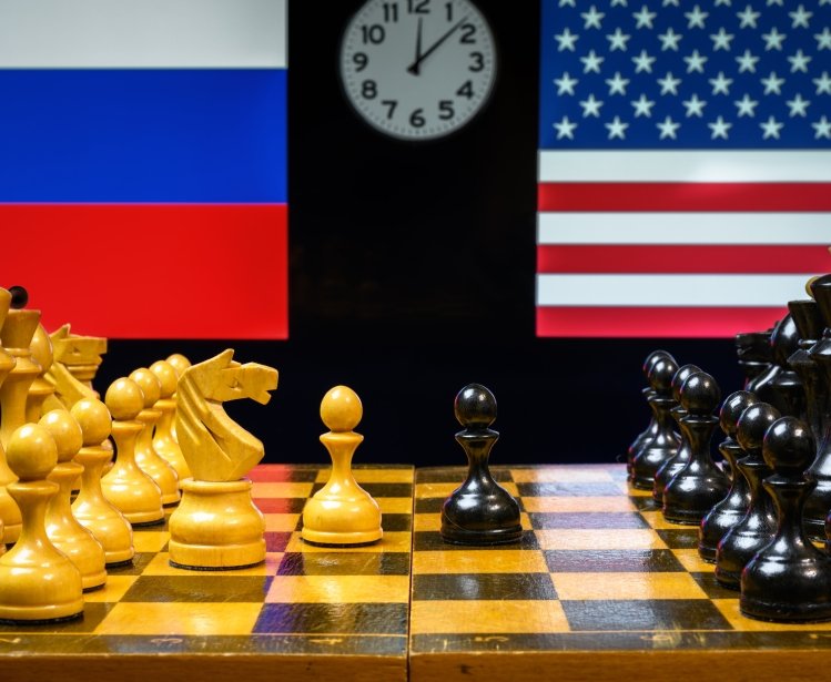 Chess board in foreground, US and Russian flags in background