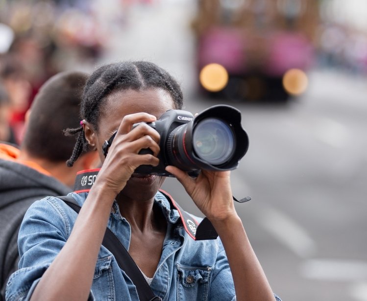Portland, OR / USA - June 11 2016: Grand floral parade, African American female photographer taking pictures with canon dslr camera.