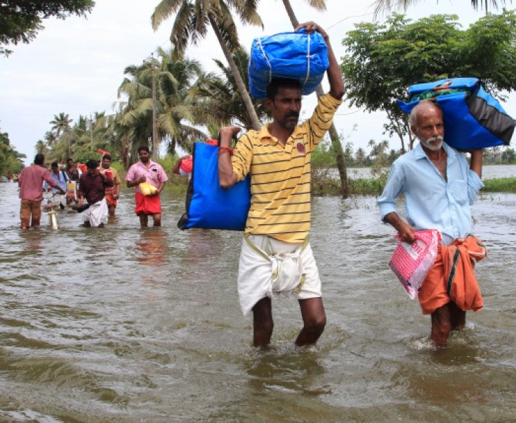 Unidentified people walk through flood water in Alleppey, Kerala, India
