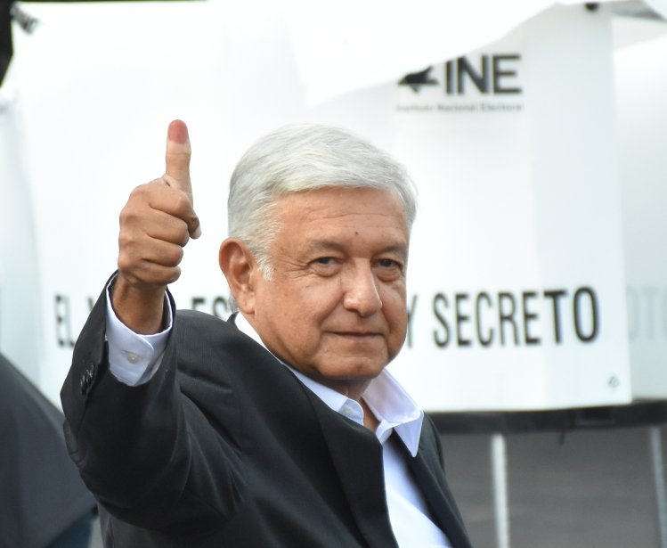 AMLO gives a thumbs up with his ink-stained finger.
