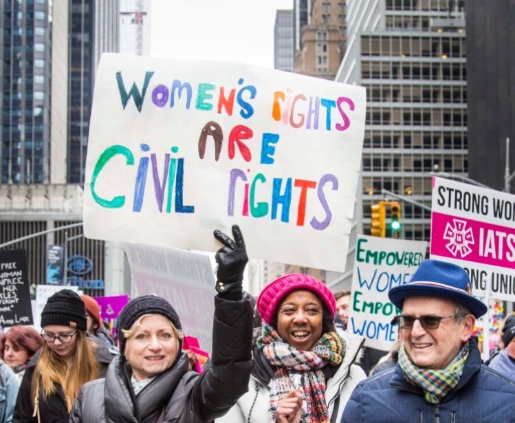 Group of people walking together – sign reads “Women’s Rights are Civil Rights” in Midtown Manhattan during the NYC Women’s March – New York, NY, USA January 1/19/2019 Women’s March.