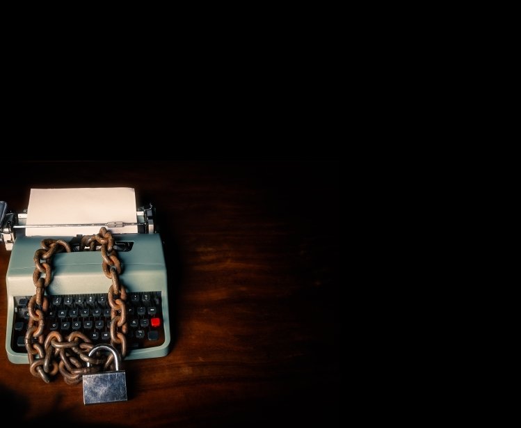 Typewriter locked with a chain and padlock on a black background