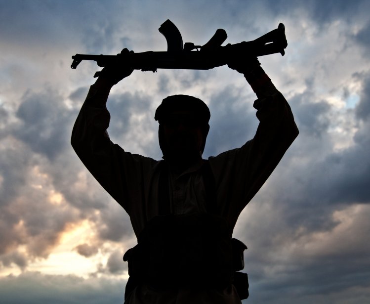 Silhouette of a man holding a large gun