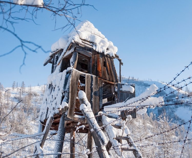 Ruins of wooden prison observation tower of labour camp GULAG in Verkhoyansk Range in Yakutia during cold winter day, Russia. The construction of the Kolyma highway aka Road of bones