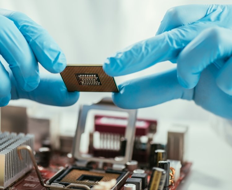 partial view of engineer holding microchip near computer motherboard
