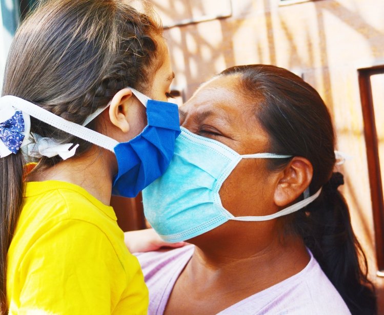 Mother and child touch noses while wearing face masks.