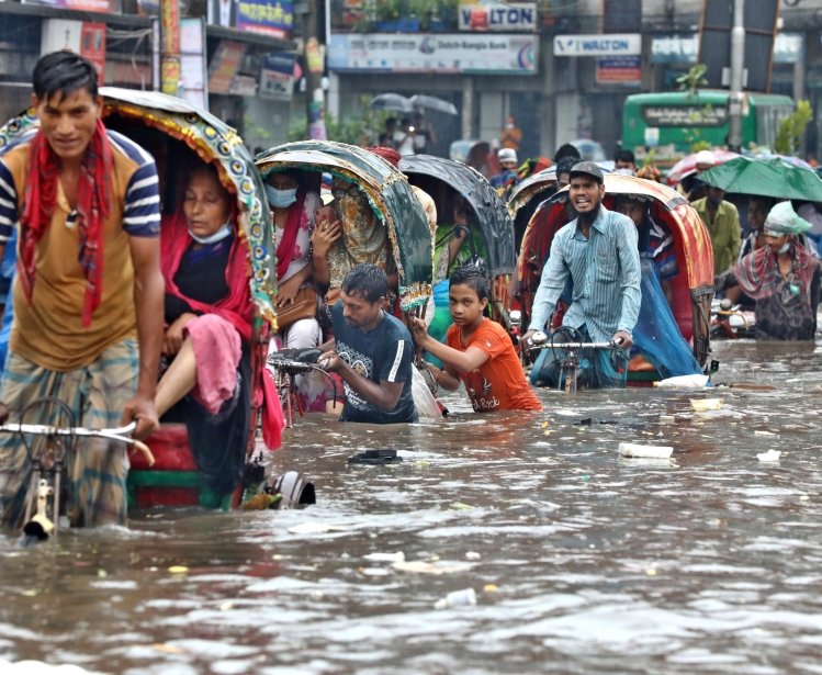 Vehicles try to drive through a flooded street in Dhaka, Bangladesh.