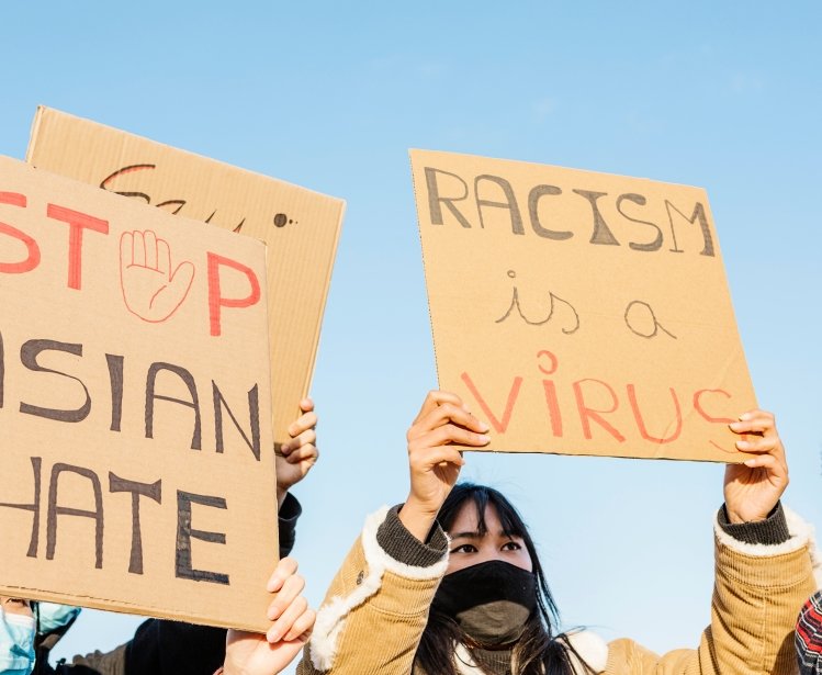 Signs of protestors, "Stop Asian Hate" and "Racism is a Virus"