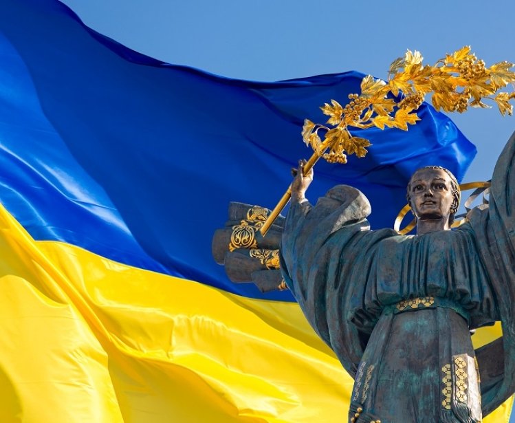 Monument of Independence of Ukraine in front of the Ukrainian flag. The monument is located in the center of Kyiv on Independence Square.