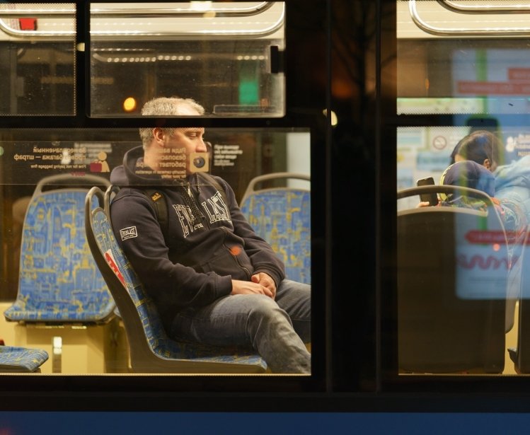 Image of a man on a bus through the bus's window 