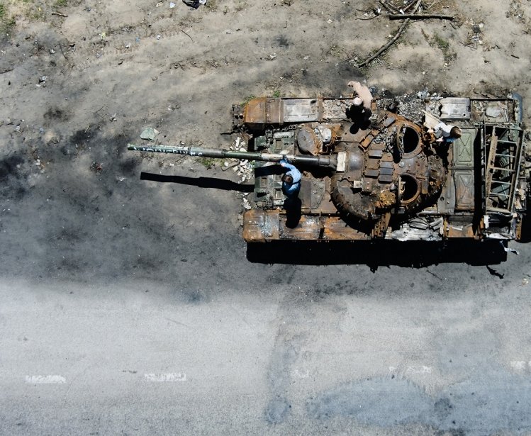 People climb on a destroyed russian tank after russian attack in Febrary