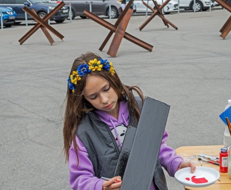Young person painting wearing flower crown with Ukrainian National Colors