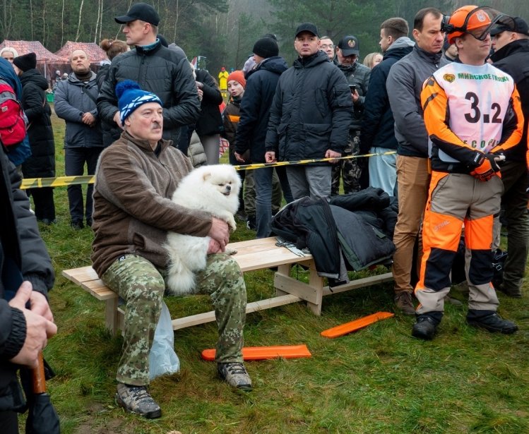President Lukashenko sitting with a small white dog among a crowd of people 