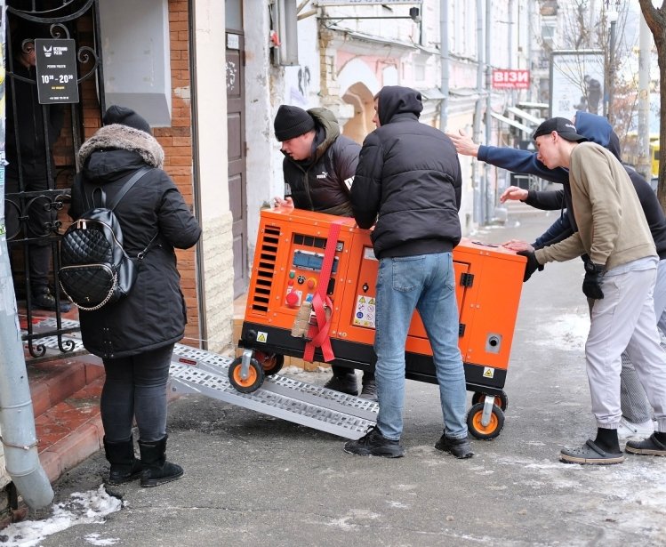 Group of men bringing an orange generator through a doorway