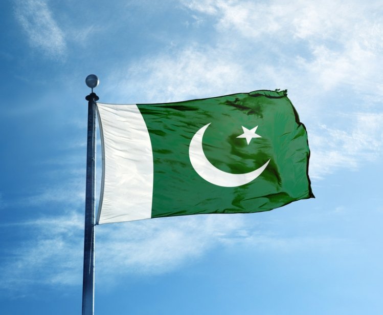 Pakistan flag against blue sky with some white clouds