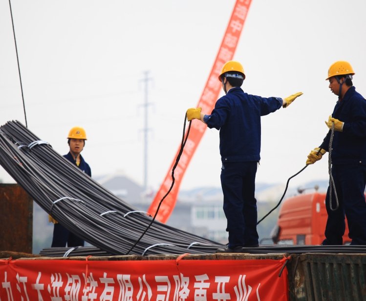 China's eastern city of Jiujiang, workers in the steel building materials market hoisting steel