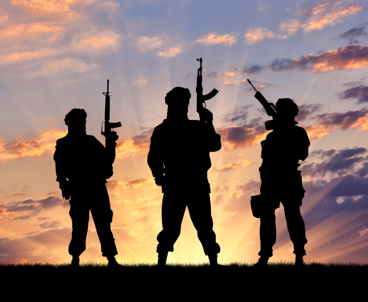 Concept of a terrorist. Silhouette terrorists with rifle at sunset